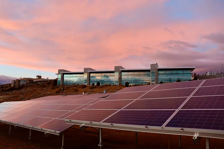 Solar energy panels installed near a modern building at sunset