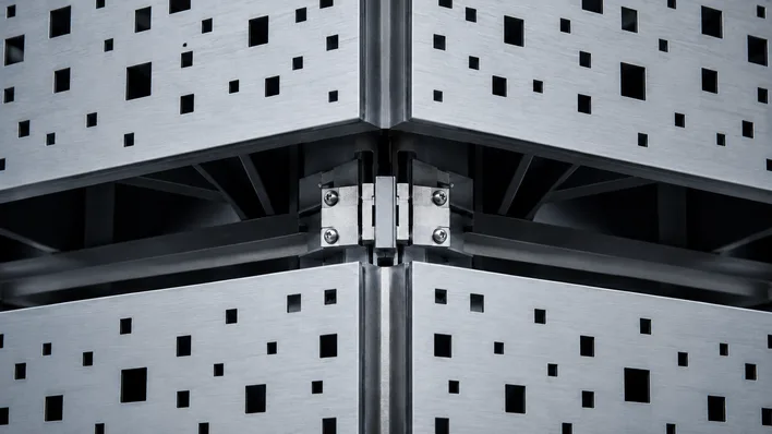 Close-up of a precision-engineered aluminum facade panel with crisp geometric edges and exposed structural detail, illustrating the millimeter-accurate output Rhino's NURBS workflow delivers